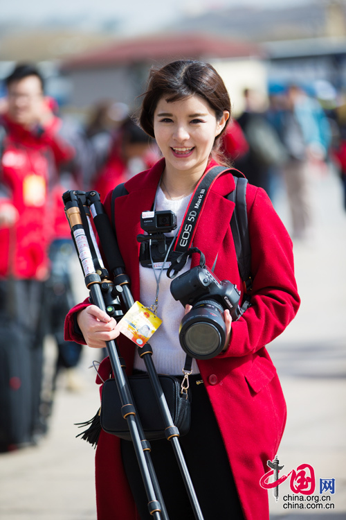 2016年兩會(huì)，人民大會(huì)大堂前，一位笑容燦爛的紅衣女記者正步入大會(huì)堂。中國(guó)網(wǎng) 鄭亮 攝